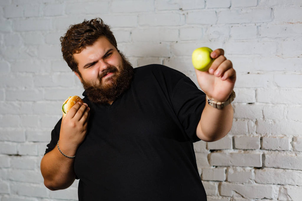 Portrait of man choosing between hamburger and green apple - Φωτογραφία, εικόνα