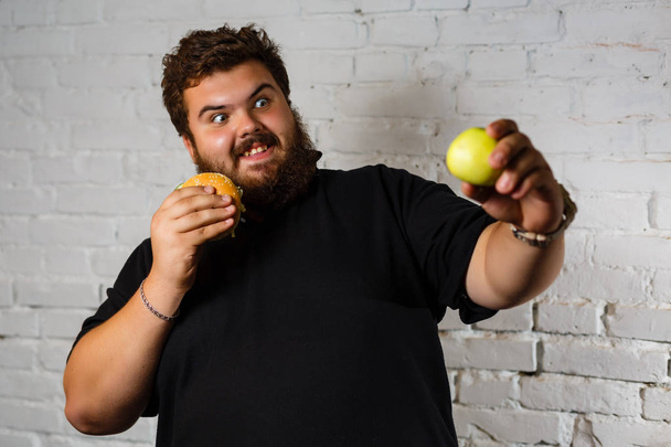 Excited bearded man greedily eating hamburgers isolated on white background - Photo, Image