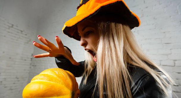 sorcière portant un chapeau orange jetant un sort sur la citrouille
   - Photo, image