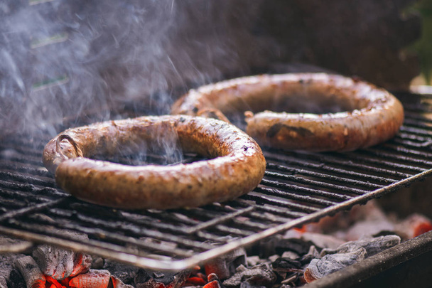 Domowe kiełbasy Barbecue-Grill gotowanie i palenie zbliżenie węgiel drzewny ogień pod - Zdjęcie, obraz