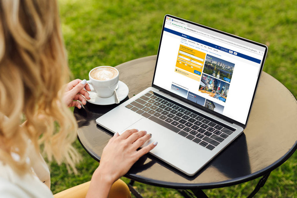cropped image of woman using laptop with loaded booking page on table in garden - Foto, Imagem