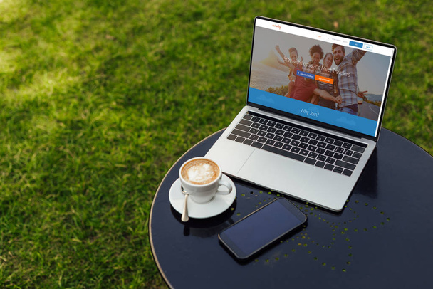 laptop with loaded couchsurfing page on table in garden - Фото, изображение