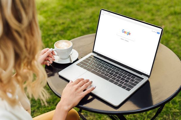 cropped image of woman using laptop with loaded google page on table in garden - Fotó, kép
