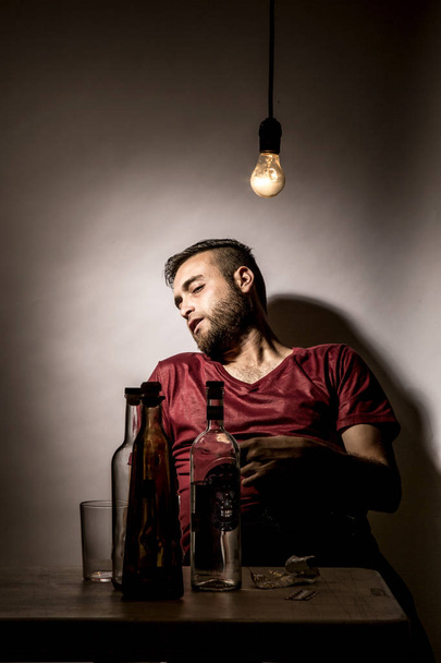 Young man with beard, lost in the vices of alcoholism, smoking and drug addiction - Fotó, kép