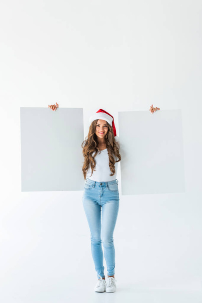 beautiful young woman in santa hat holding empty boards, isolated on white - Φωτογραφία, εικόνα
