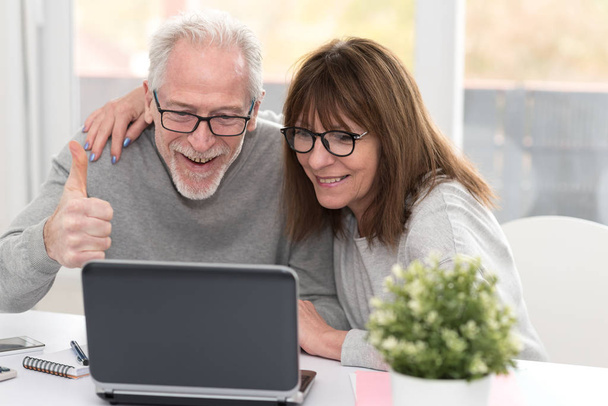 Happy mature couple having an amazing surprise on laptop - Photo, Image