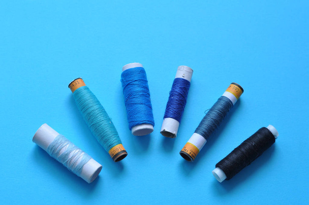 blue thread reels for sewing on a blue background. photo thread on. threads of shades of blue. sewing, needlework, handmade. Use for backgrounds, wallpapers, posters, advertisements, card - Fotoğraf, Görsel