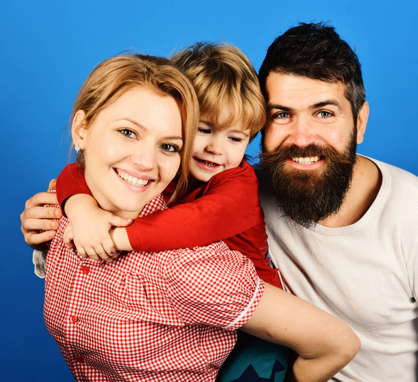 Mother, father and son with smiling faces hug on blue - Foto, afbeelding