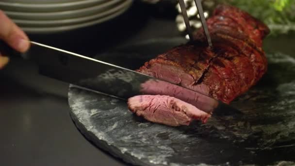 Slicing a medium rare steak into thin parts for Christmas Dinner on a restaurant. - Filmati, video
