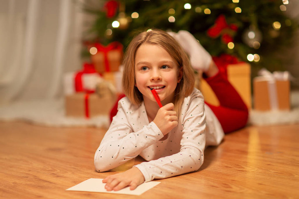 smiling girl writing christmas wish list at home - Foto, afbeelding