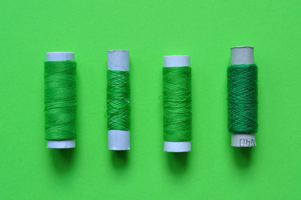 bobine di filo verde per cucire su uno sfondo verde. filo della foto sopra. fili di ombre di verde. cucito, cucito, fatto a mano. Uso per sfondi, sfondi, manifesti, pubblicità, carta
 - Foto, immagini