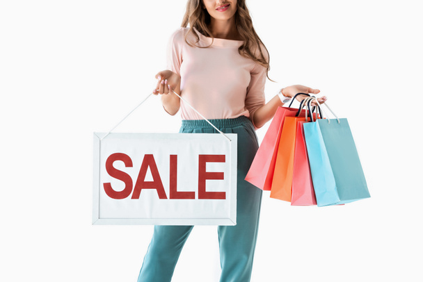 Ausgeschnittene Ansicht einer Frau mit Verkaufsschild und Einkaufstaschen, isoliert auf weiß - Foto, Bild