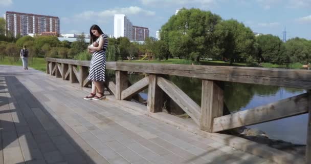 Girl with a child on a wooden bridge - Кадры, видео