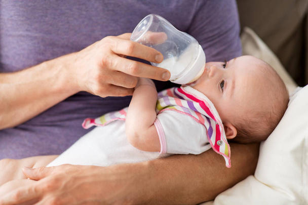 close up of father feeding baby from bottle - Фото, изображение