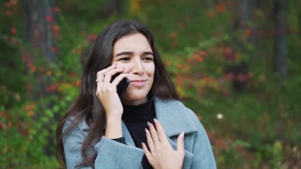 Woman talking on a mobile cell phone at park close up - Felvétel, videó