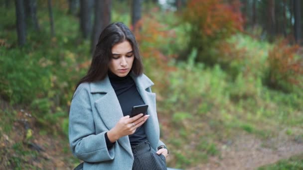 Happy young woman sending sms, texting in the park - Footage, Video