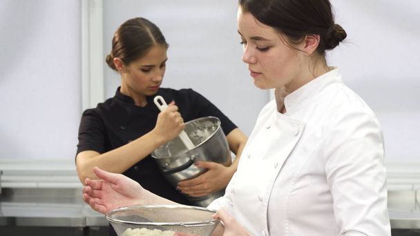 Молода приваблива жінка шеф-кухарка посміхається до камери під час приготування їжі
 - Фото, зображення
