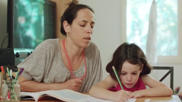 Matka, pomagając jej córeczkę do przygotowania domowych w domu - Materiał filmowy, wideo