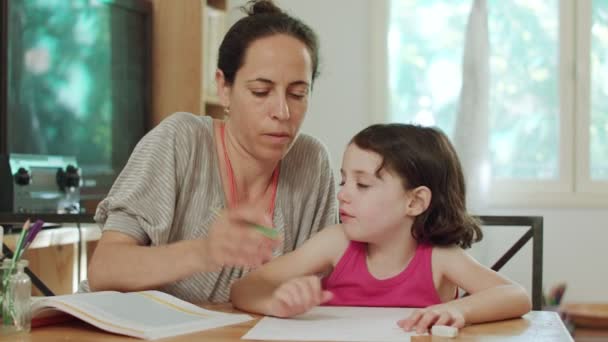 Η μητέρα βοηθά τη μικρή της κόρη να προετοιμάσει την εργασία στο σπίτι - Πλάνα, βίντεο
