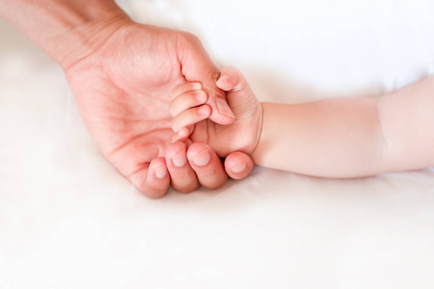 Father holding the hand of his new born son, shallow DOF. Tust, support, security and care concept - Fotografie, Obrázek