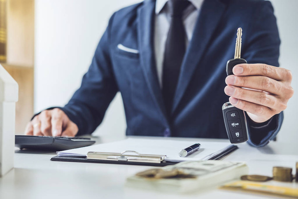 Salesman holding a key and calculating a price of selling new car and home loan, transportation and ownership concept. - Fotografie, Obrázek