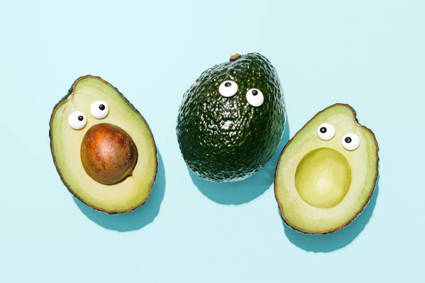 Funny faces avocados on a pastel blue background, creative healthy food concept, top view with clipping path - Photo, Image