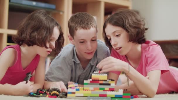 Tři děti hrát si s lego kostkami doma - Záběry, video