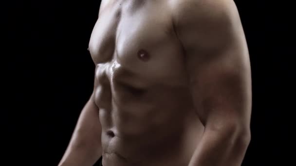Homem mostra um corpo forte muscular close-up em um fundo preto
 - Filmagem, Vídeo
