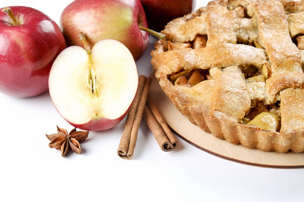 Traditional American Thanks Giving pie, whole & halved apples, cinnamon sticks, anise seeds. Homemade fruit tart baked to golden crust with ingredients. Close up, copy space, top view, background. - 写真・画像