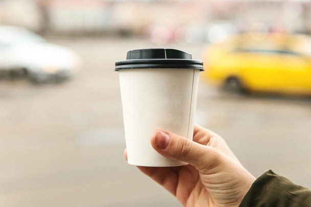 Una joven sostiene un vaso desechable con café u otra bebida caliente en la estación fría
. - Foto, imagen
