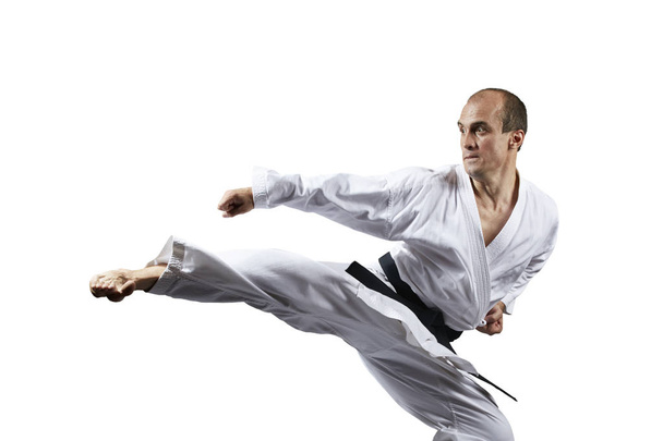 A kick struck by an athlete with a black belt on a white background isolated - Photo, Image