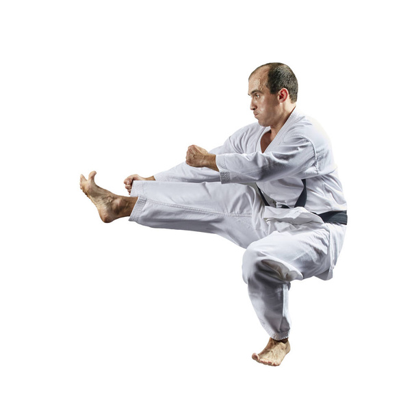 Dans karategi, un sportif adulte entraîne un coup de pied dans un saut sur un fond blanc isolé
   - Photo, image