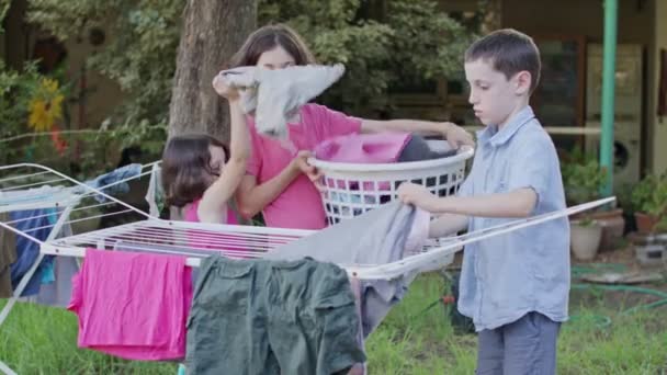 Trois enfants enlèvent la lessive de la ligne de pendaison au panier
 - Séquence, vidéo