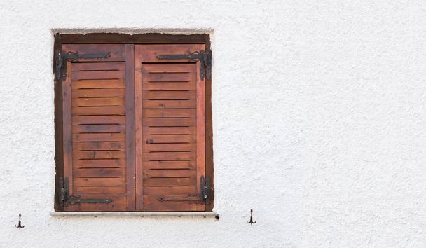 altes Holzfenster mit braunen Fensterläden, an rauer Wand. - Foto, Bild