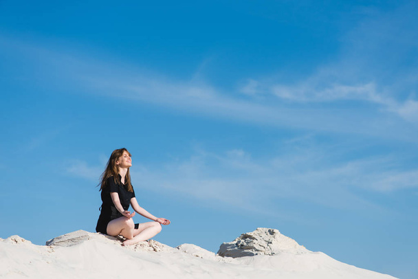 Chica sonriente en pose de loto en las dunas de arena
 - Foto, imagen
