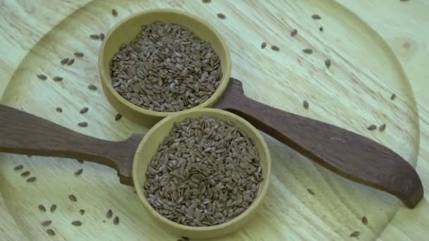 Két fakanál forgatása lenmaggal fából készült tányéron  - Felvétel, videó