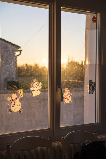 Сніговик Різдвяні прикраси застрягли на вікні з м'яким золотим зимовим світлом
 - Фото, зображення