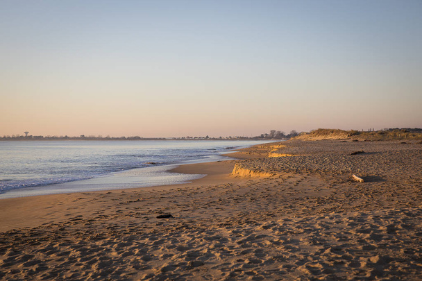 vista para uma praia ao pôr-do-sol com areia dourada e mar tranquilo
 - Foto, Imagem