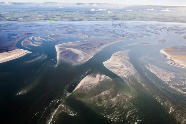 Luftaufnahme der Watt-Küste bei Ebbe mit Wasser, das sich im Schlamm und auf der Sandbank windet, der friesischen Insel Ameland, den Niederlanden - Foto, Bild