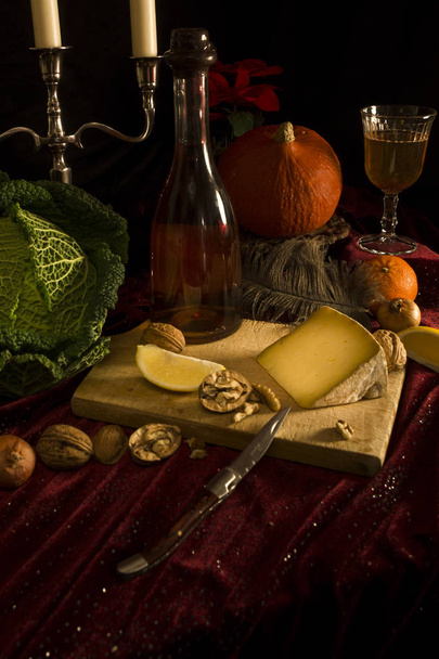 Παλιά στυλ νεκρές φύσεις με κεριά, pumkin, τυρί, λάχανο, likor μπουκάλι, φέτες λεμονιού με μαύρο φόντο - Φωτογραφία, εικόνα