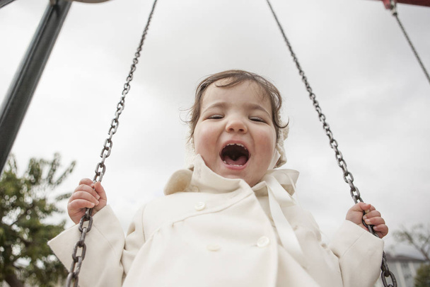 Mutlu 2 yaşındaki kız kış salıncakta eğleniyor. Seçici odak - Fotoğraf, Görsel