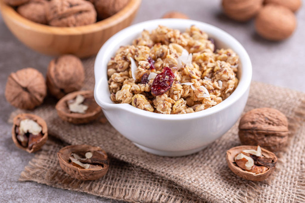 Bowl of homemade granola with nuts and raisins on grey slate background.  Horizontal view. Copy space - Fotoğraf, Görsel