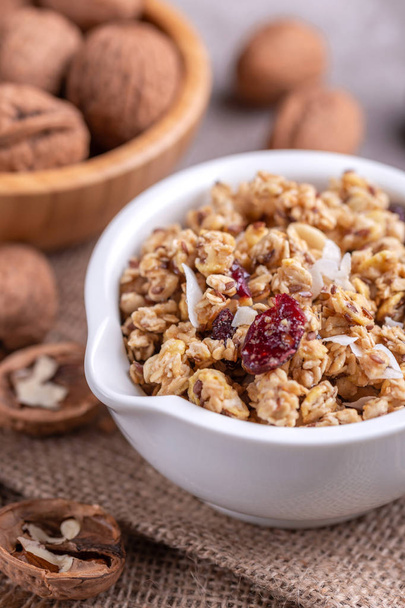 Bowl of homemade granola with nuts and raisins on grey slate background.  Horizontal view. Copy space - Photo, image