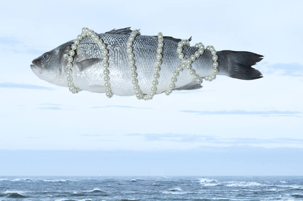 surrealistische isolierte Fische mit einer Perlenkette, die am Himmel über dem Meer schwebt, inspiriert von Magritte - Foto, Bild