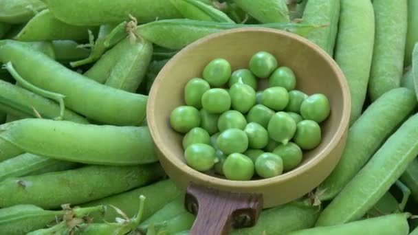 回転緑エンドウ豆の鞘と古い木のスプーンのエンドウ豆 - 映像、動画