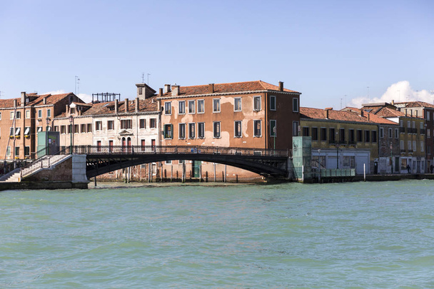 橋とオレンジの老朽化したファサードの建物とリオ・デル・ポンテ・ルンゴの入り口に表示,ヴェネツィア,イタリア - 写真・画像