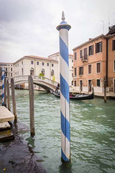 romantischer Kanal mit grün-türkisfarbenem Wasser und einem weiß-blau gestreiften Mast, Venedig, Italien - Foto, Bild