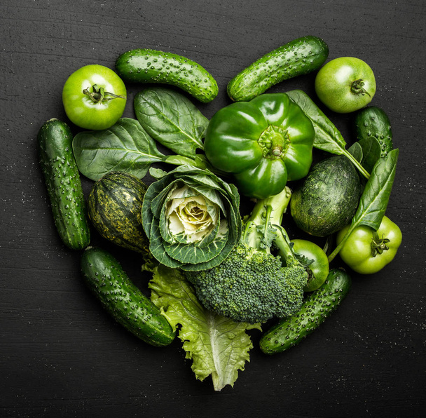 Green vegetables arranged in heart shape on rustic stone table. Vegetarian concept of healthy eating, top view - Foto, afbeelding