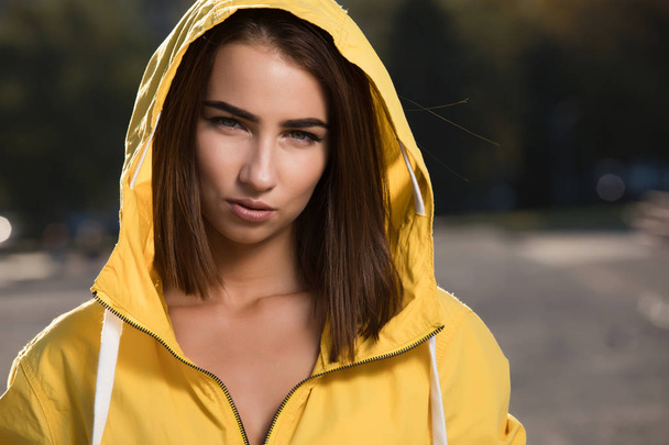 Confident serious woman outdoor portrait under yellow hood - Foto, afbeelding