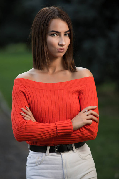 Portrait of confident strict woman in red sweater at the autumn park with arms crossed - Photo, Image